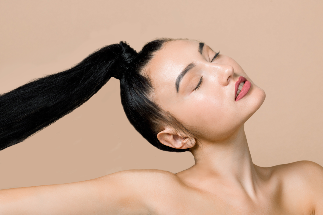 A woman with sleek, healthy hair in a high ponytail looking confident.