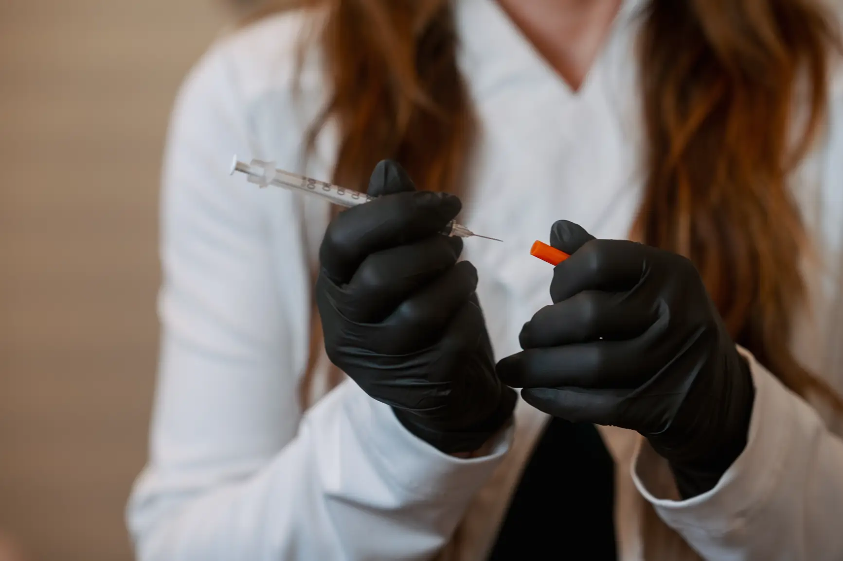 Medical provider wearing gloves holding syringe and needle