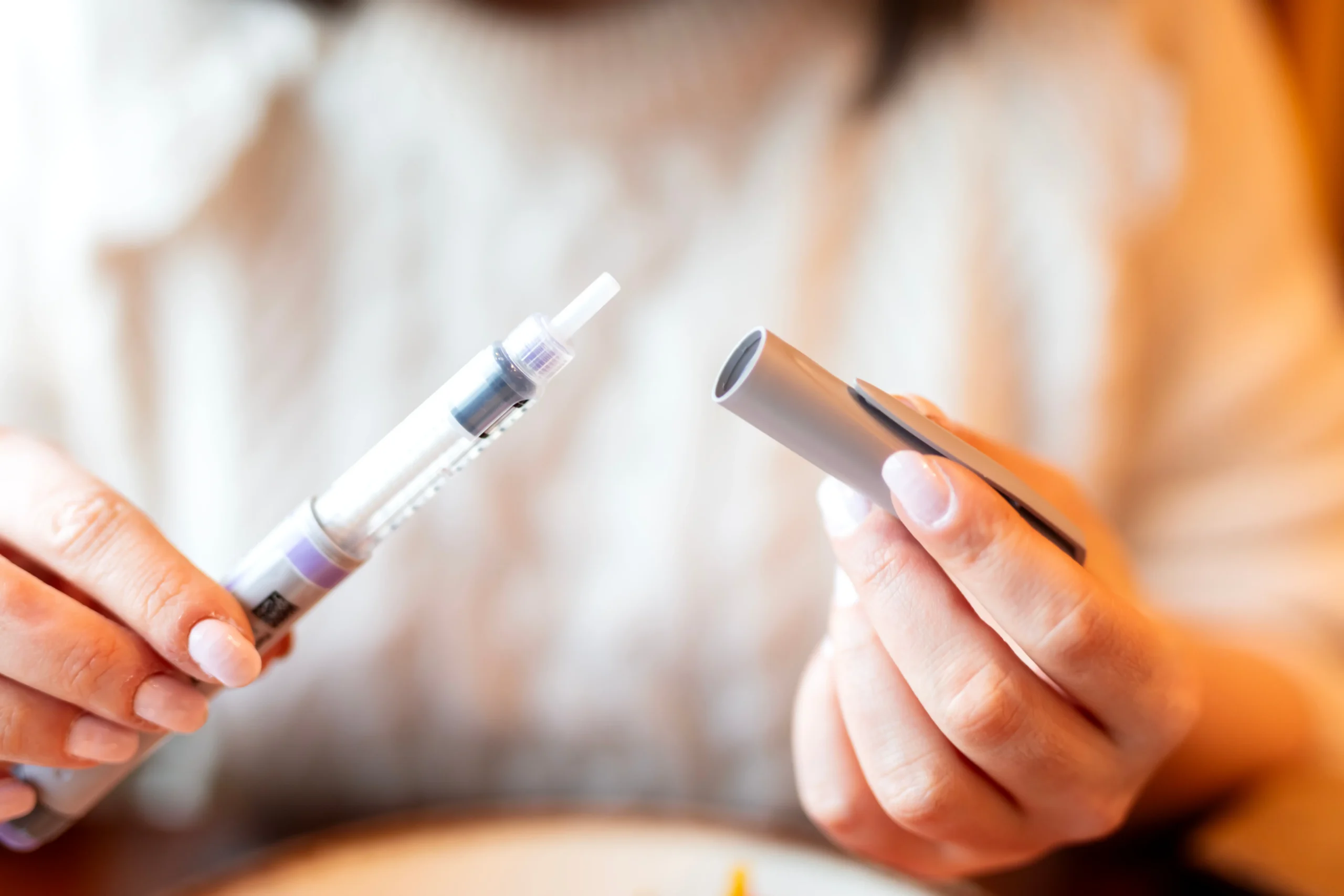 Person holding an injection pen with the cap removed before use