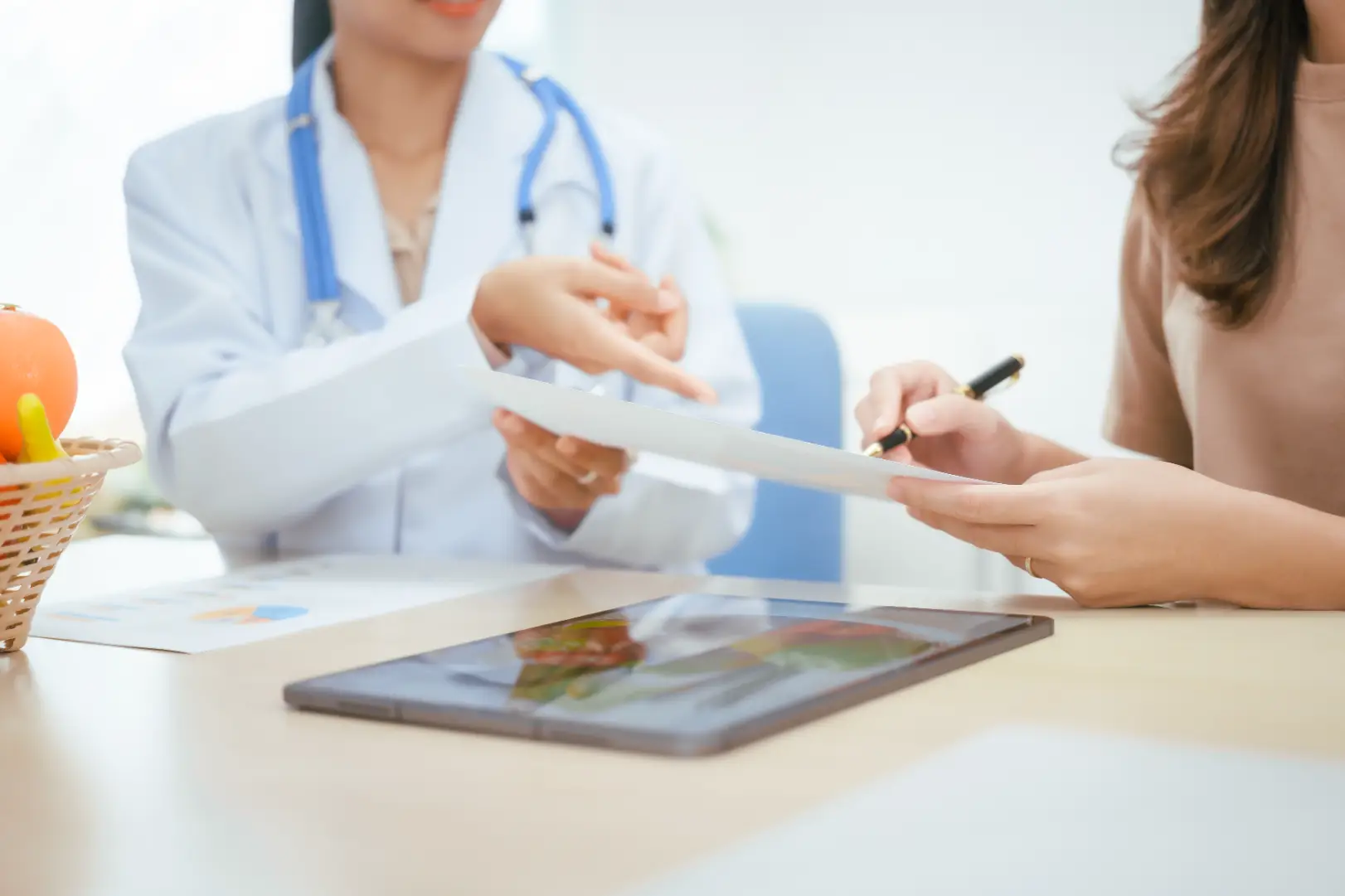 Healthcare professional reviewing paperwork with a patient during a medical consultation.